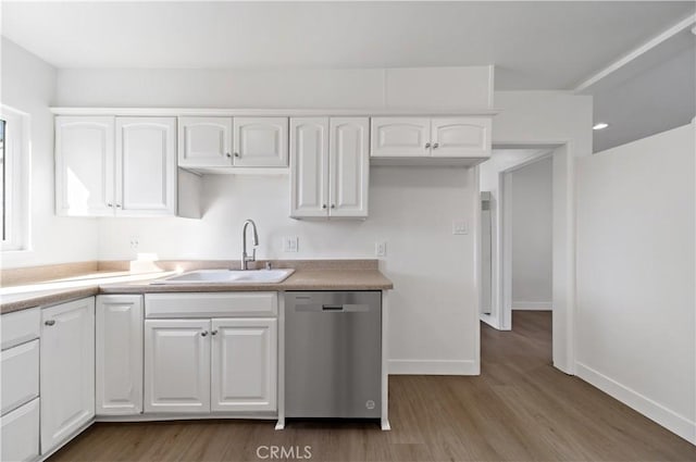 kitchen with light wood finished floors, a sink, white cabinets, and stainless steel dishwasher