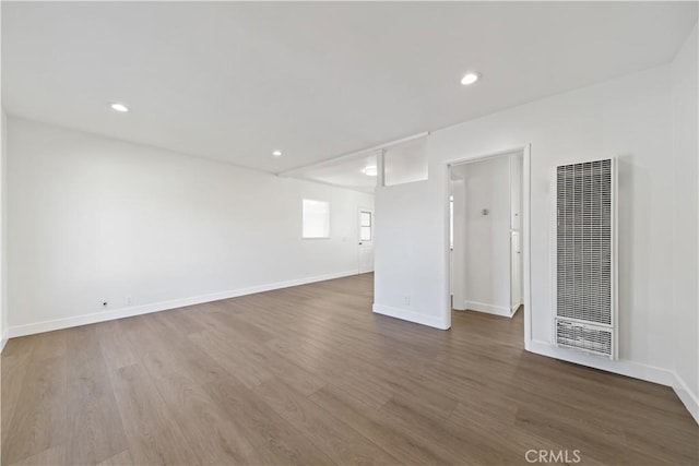 unfurnished room with recessed lighting, baseboards, wood finished floors, and a heating unit