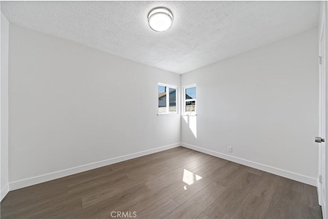 unfurnished room with baseboards, a textured ceiling, and wood finished floors