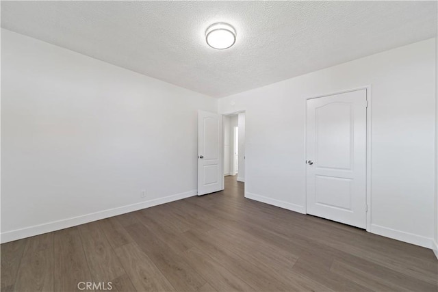 unfurnished bedroom featuring baseboards, a textured ceiling, and wood finished floors