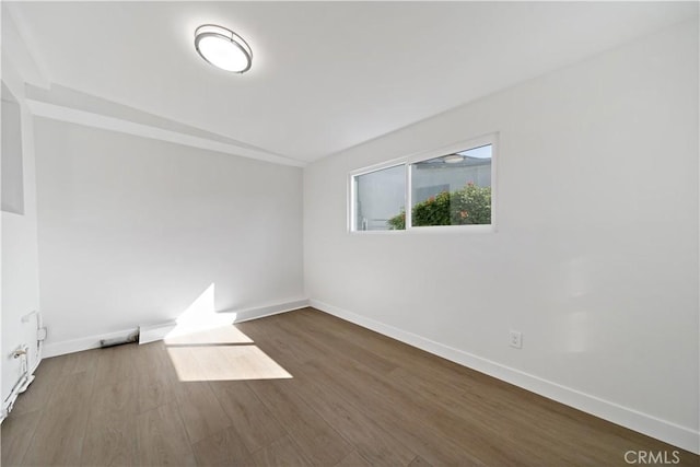 spare room featuring baseboards and dark wood-style flooring