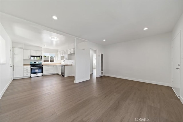 unfurnished living room with recessed lighting, dark wood-type flooring, and baseboards