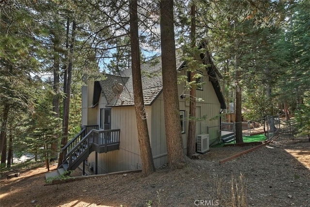 view of side of property featuring ac unit, fence, and a shingled roof