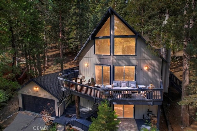 rear view of house featuring concrete driveway, stairway, an outdoor living space, and a wooden deck