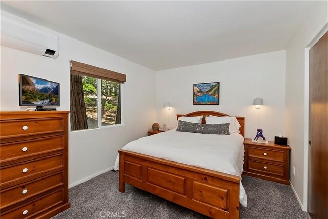 bedroom featuring baseboards, an AC wall unit, and dark carpet