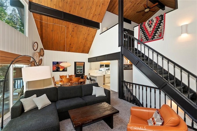 carpeted living room with beam ceiling, high vaulted ceiling, wood ceiling, and a ceiling fan
