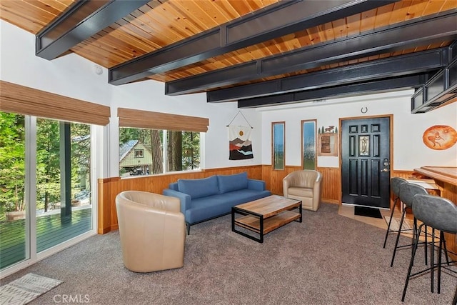living area with a wainscoted wall, beam ceiling, wooden walls, and carpet flooring