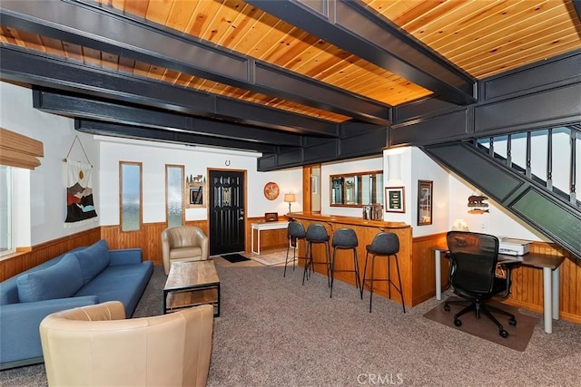 living area featuring beamed ceiling, carpet flooring, a wainscoted wall, and wood walls
