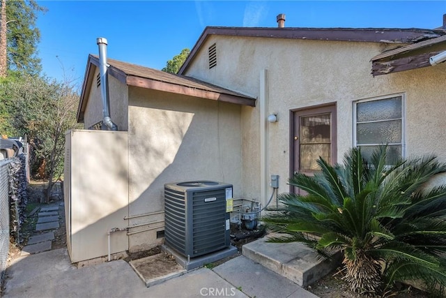 exterior space with central air condition unit, fence, and stucco siding