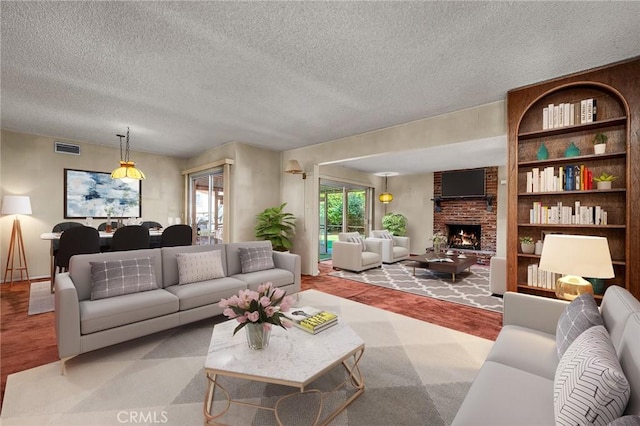 living room featuring visible vents, built in shelves, a textured ceiling, and a fireplace