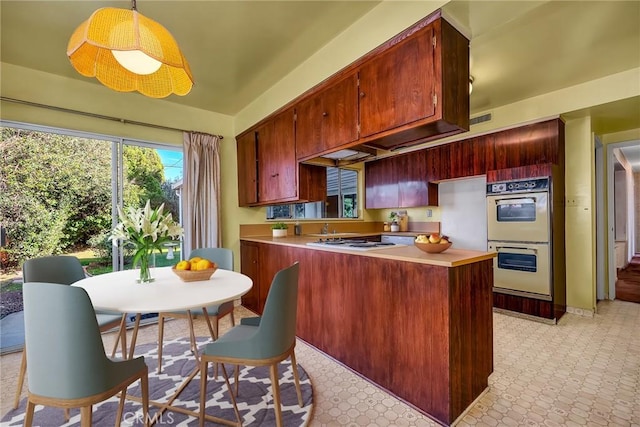 kitchen with white appliances, light floors, visible vents, a peninsula, and light countertops