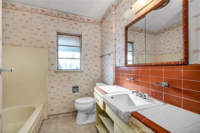 bathroom featuring vanity, a bathing tub, wallpapered walls, tile patterned flooring, and toilet