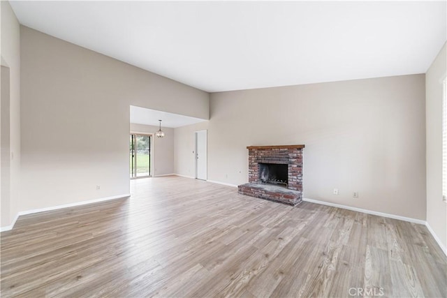 unfurnished living room with light wood-type flooring, baseboards, a fireplace, and vaulted ceiling