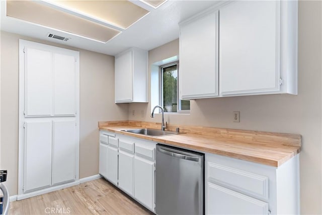 kitchen featuring light wood finished floors, visible vents, stainless steel dishwasher, white cabinets, and a sink