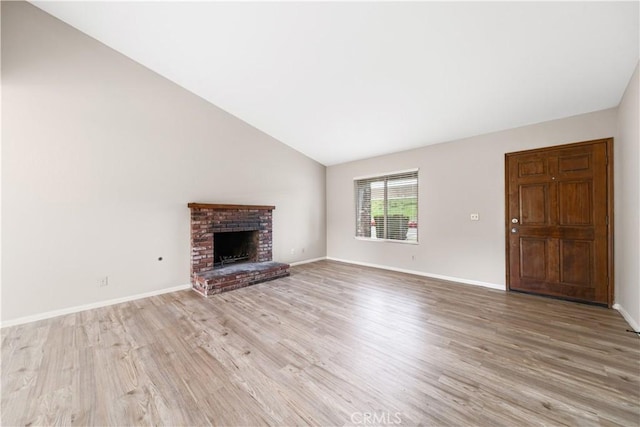 unfurnished living room with baseboards, a fireplace, vaulted ceiling, and light wood finished floors