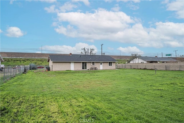 rear view of house featuring a yard and a fenced backyard