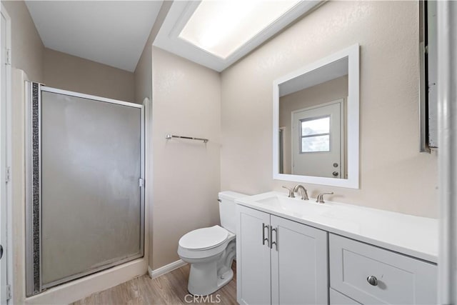 full bath featuring vanity, a shower stall, toilet, and wood finished floors