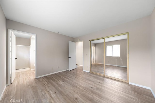 unfurnished bedroom with light wood-style floors, a closet, and baseboards