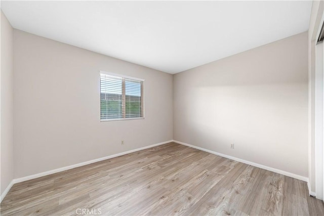 unfurnished room with baseboards and light wood-style floors