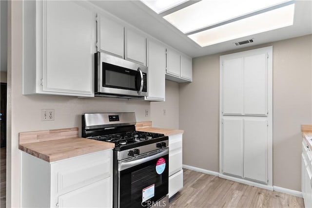 kitchen with visible vents, light wood-style flooring, white cabinetry, stainless steel appliances, and light countertops