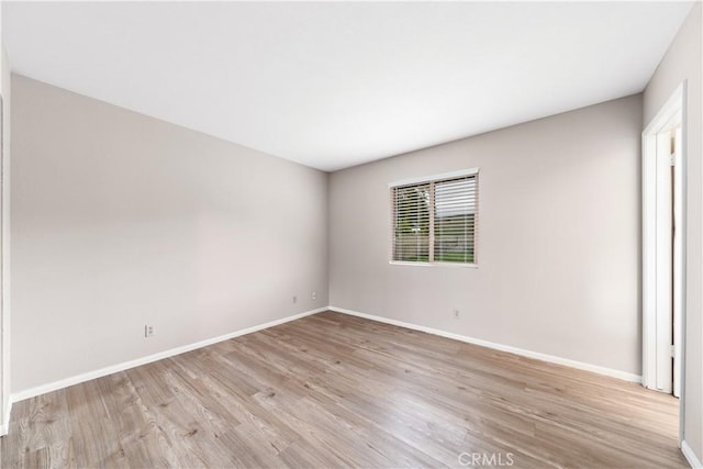 empty room featuring light wood-type flooring and baseboards