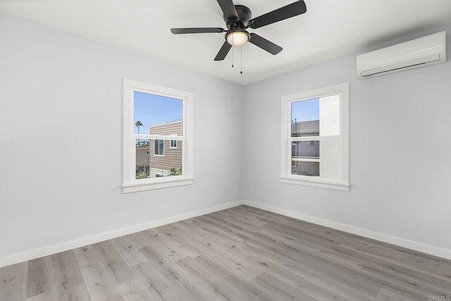 empty room with baseboards, ceiling fan, a wall unit AC, and wood finished floors
