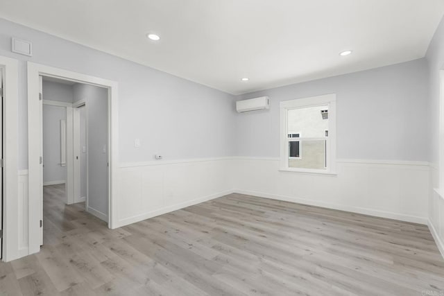 spare room with light wood-style flooring, wainscoting, recessed lighting, and a wall mounted air conditioner