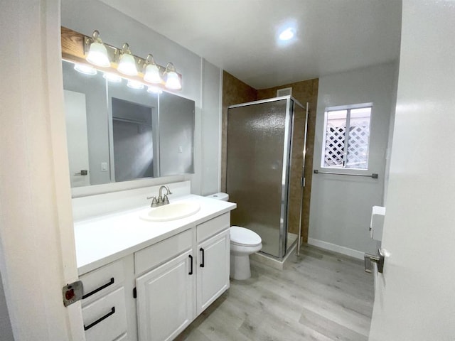 bathroom with a shower stall, wood finished floors, vanity, baseboards, and toilet
