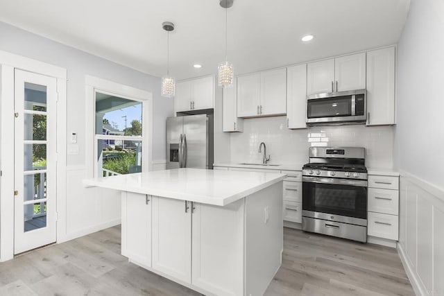 kitchen featuring a sink, white cabinets, stainless steel appliances, and light wood-style flooring