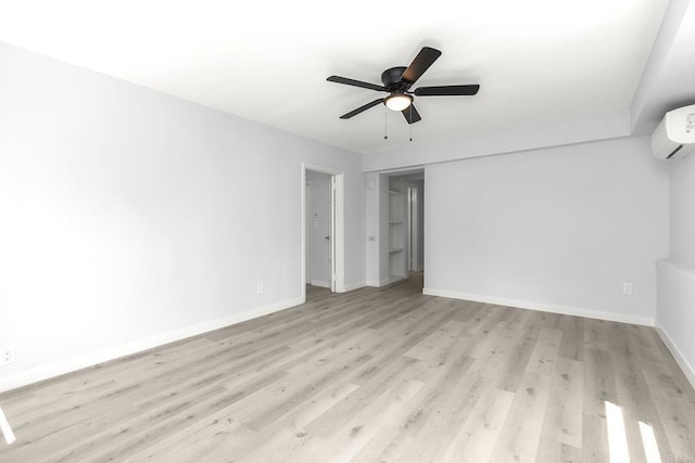 unfurnished bedroom featuring baseboards, ceiling fan, an AC wall unit, and light wood-style flooring