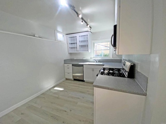 kitchen featuring appliances with stainless steel finishes, light wood-style flooring, a sink, track lighting, and white cabinetry