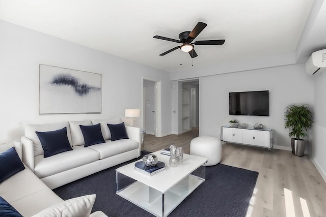 living area featuring a ceiling fan, baseboards, a wall mounted AC, and light wood-style floors