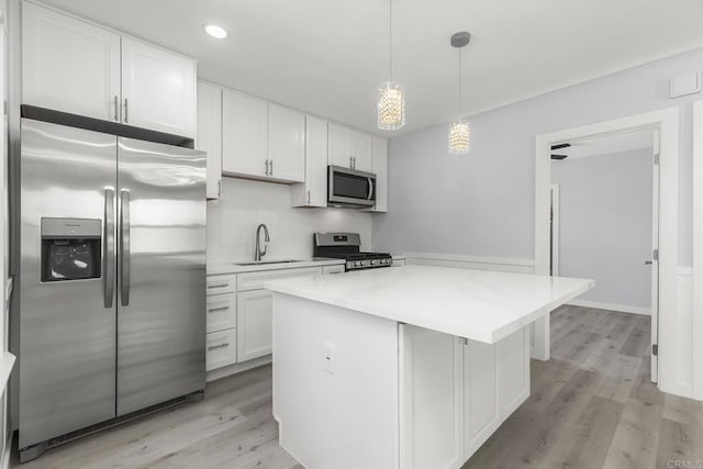 kitchen with white cabinetry, appliances with stainless steel finishes, a sink, and a center island