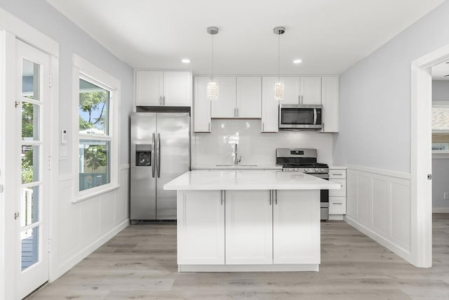 kitchen with white cabinets, stainless steel appliances, a sink, and a decorative wall