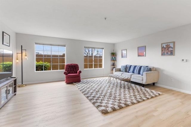 living room with a healthy amount of sunlight, light wood-type flooring, and baseboards