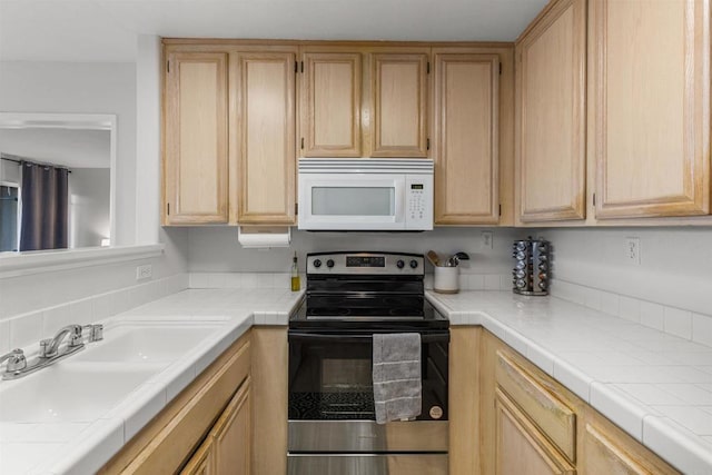 kitchen featuring white microwave, tile counters, light brown cabinetry, stainless steel range with electric cooktop, and a sink