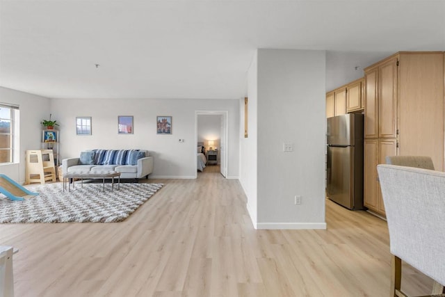 living area featuring baseboards and light wood finished floors