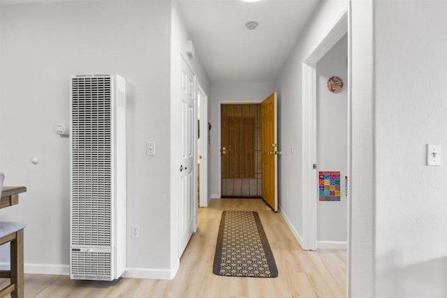 hall featuring baseboards, a heating unit, and light wood-type flooring