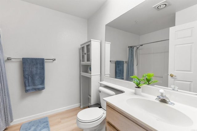 bathroom with vanity, a shower with shower curtain, wood finished floors, baseboards, and toilet