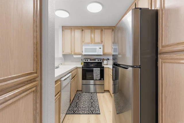 kitchen featuring a sink, stainless steel appliances, light brown cabinetry, and light countertops