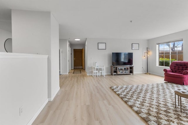 unfurnished living room featuring baseboards and wood finished floors