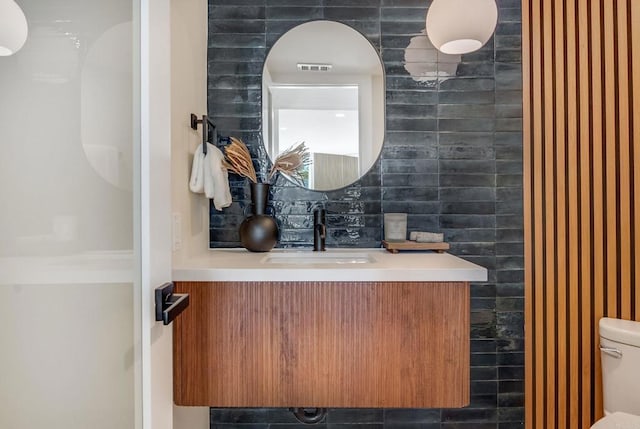 bathroom with tile walls, visible vents, toilet, and vanity