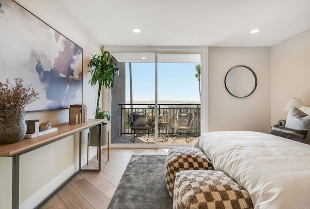 bedroom with access to outside, recessed lighting, wood finished floors, and expansive windows