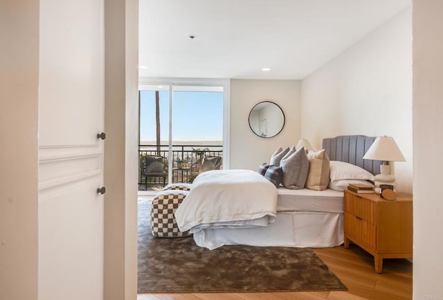 bedroom with light wood-style flooring, a wall of windows, and access to outside