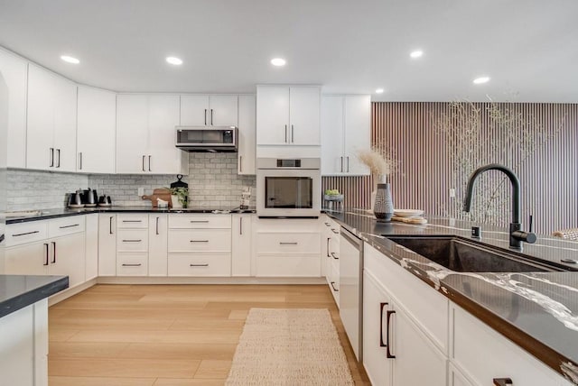 kitchen featuring dark countertops, light wood finished floors, appliances with stainless steel finishes, and a sink