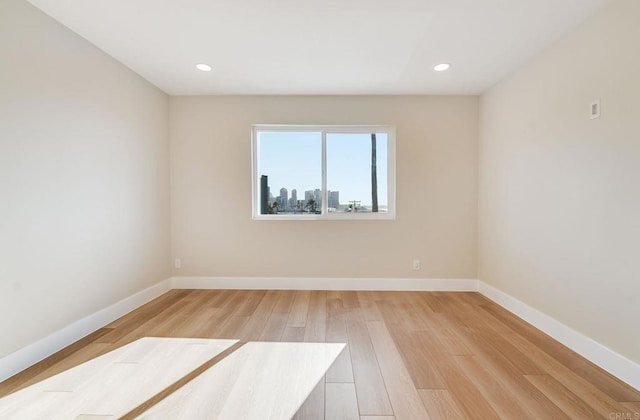 spare room with recessed lighting, light wood-type flooring, and baseboards