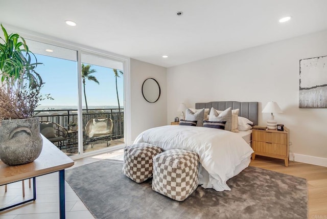 bedroom featuring access to exterior, light wood finished floors, baseboards, a wall of windows, and recessed lighting