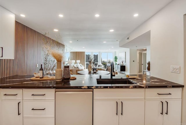 kitchen featuring dishwashing machine, open floor plan, a sink, recessed lighting, and white cabinetry