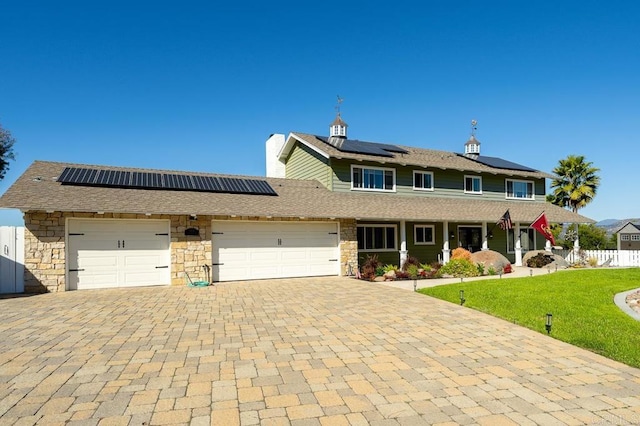 view of front of property featuring a front lawn, covered porch, decorative driveway, a garage, and stone siding