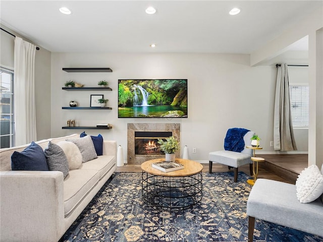 living room featuring recessed lighting, a premium fireplace, baseboards, and wood finished floors